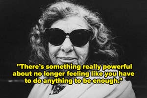Elderly person wearing large sunglasses, looking directly at the camera with a slight smile, wrapped in a shawl